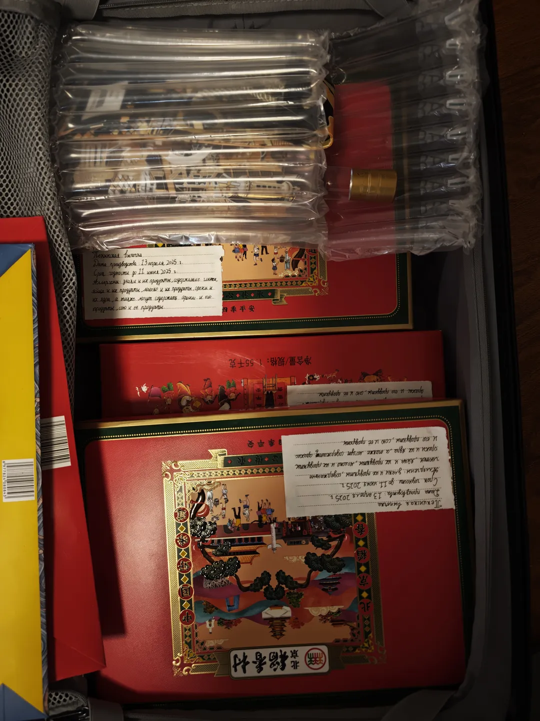 An open suitcase contains multiple beautifully packaged items. Chinese labels and decorative patterns appear on the items. The internal structure of the suitcase is clearly visible.