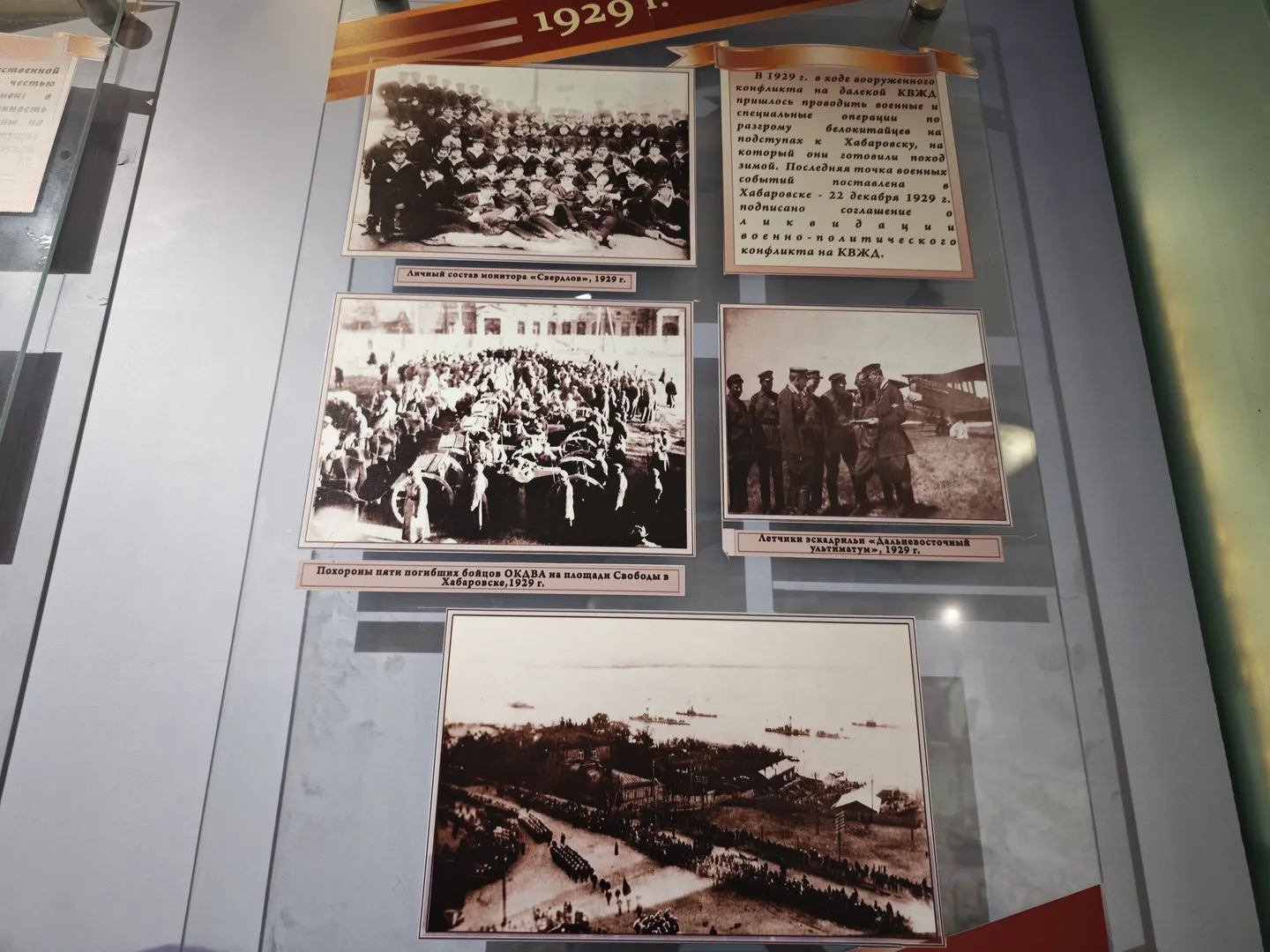 Several historical photos are displayed on the wall, including a group photo of uniformed individuals, a funeral scene, and naval fleet photos. The accompanying text describes historical events from 1929 and related details. Below the photos, there are Russian captions.