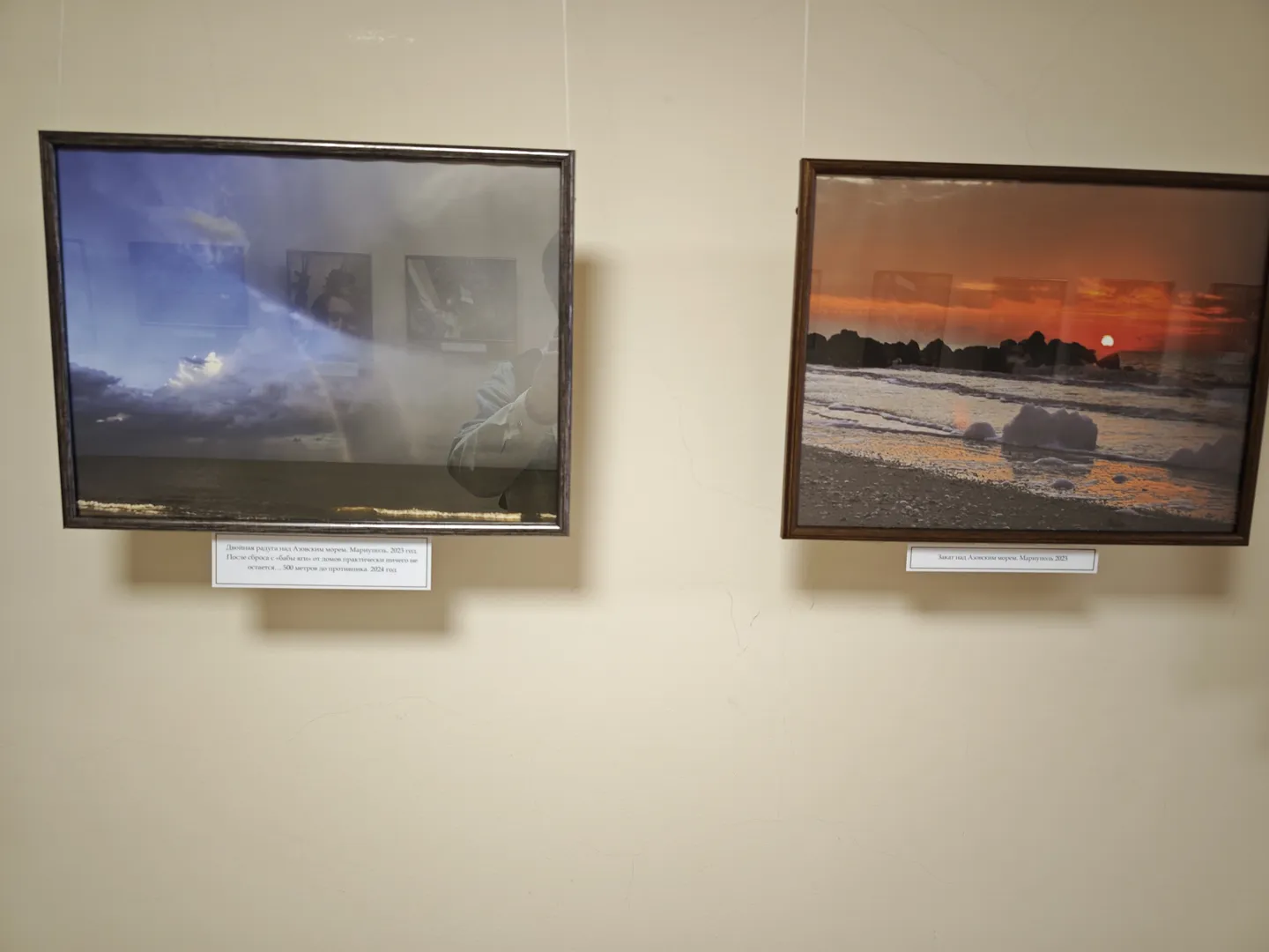 Two paintings on the wall. On the left, a lightning scene at sea; on the right, a sunset at the seaside. Each painting has a white label with a description below.