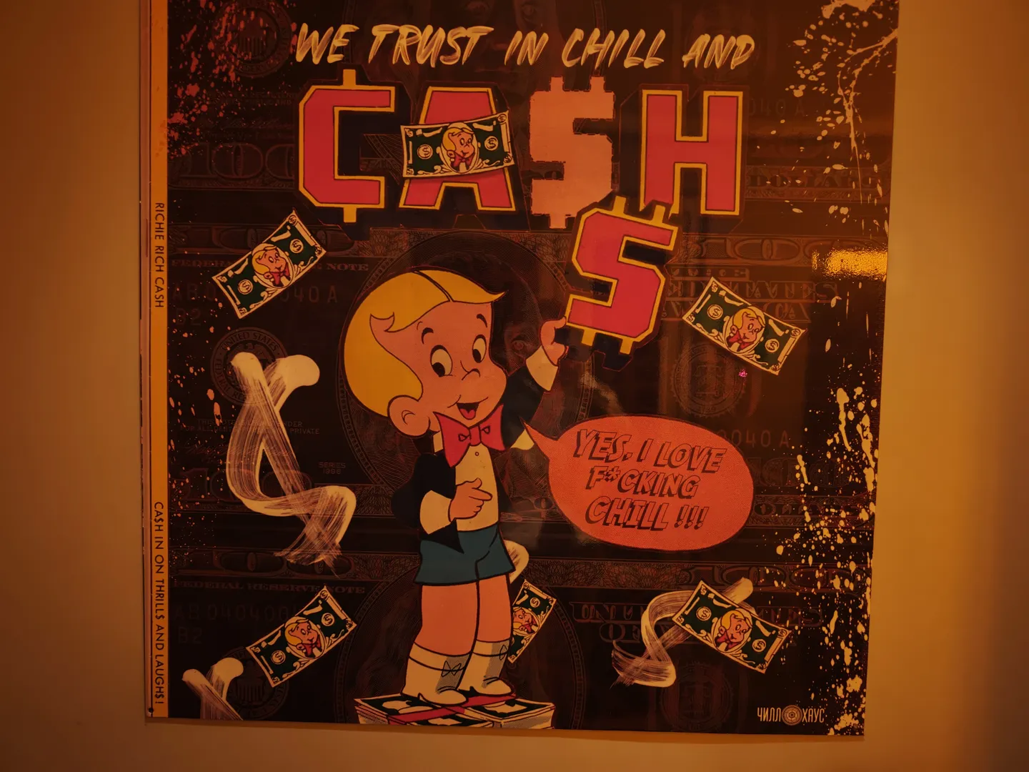 A cartoon boy stands on a pile of money, holding a letter “S” with a dollar symbol. The background shows several dollar bill patterns and the text “WE TRUST IN CHILL AND CASH”. A speech bubble next to the boy reads “YES, I LOVE F**CKING CHILL!!!”.