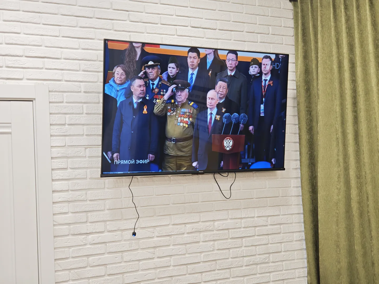 The hotel TV is playing a parade celebrating the 80th anniversary of the victory in the Great Patriotic War. The screen shows a group photo of national leaders. Due to the presence of President Xi Jinping, this image cannot be used to generate a description with the large model.