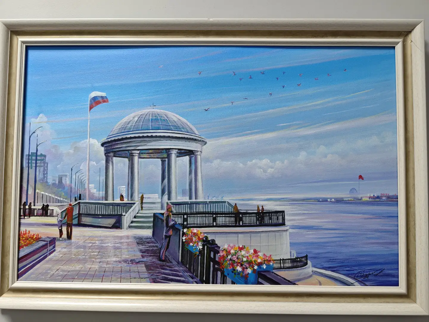 一幅白色画框中的油画，描绘了一个临水的圆形亭子，亭子由多根柱子支撑，顶部为玻璃穹顶。画面左侧有行人和旗帜，右侧是宽阔的水面，远处可见城市轮廓和飞翔的鸟群。前景中有花坛和栏杆，整体色调明亮。