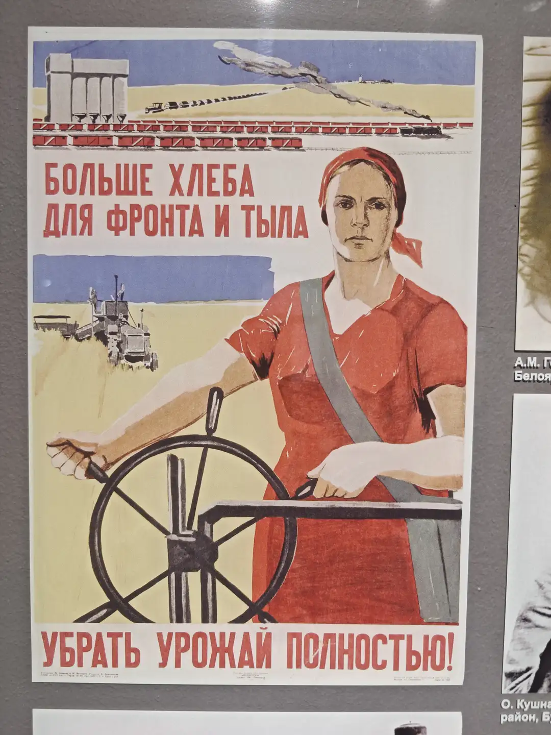 一幅宣传海报上写着“БОЛЬШЕ ХЛЕБА ДЛЯ ФРОНТА И ТЫЛА”和“УБРАТЬ УРОЖАЙ ПОЛНОСТЬЮ!”，画面中一位穿红色衣服的女性正在操作农业机械，背景是农田、拖拉机和火车。天空中有飞机飞过，整体色调以红色和黄色为主。