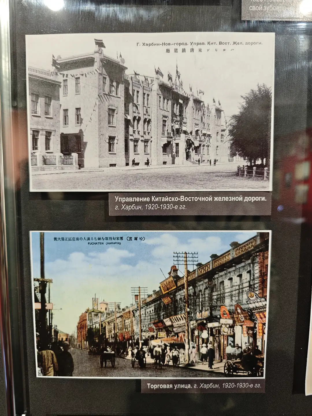 哈尔滨中东铁路管理局大楼，建筑风格融合了欧式与中式元素，门前有行人走动。照片下方标注为“Управление Китайско-Восточной железной дороги. г. Харбин, 1920-1930-е гг.”街道两旁树木成行，建筑整齐排列，展现出早期城市风貌。