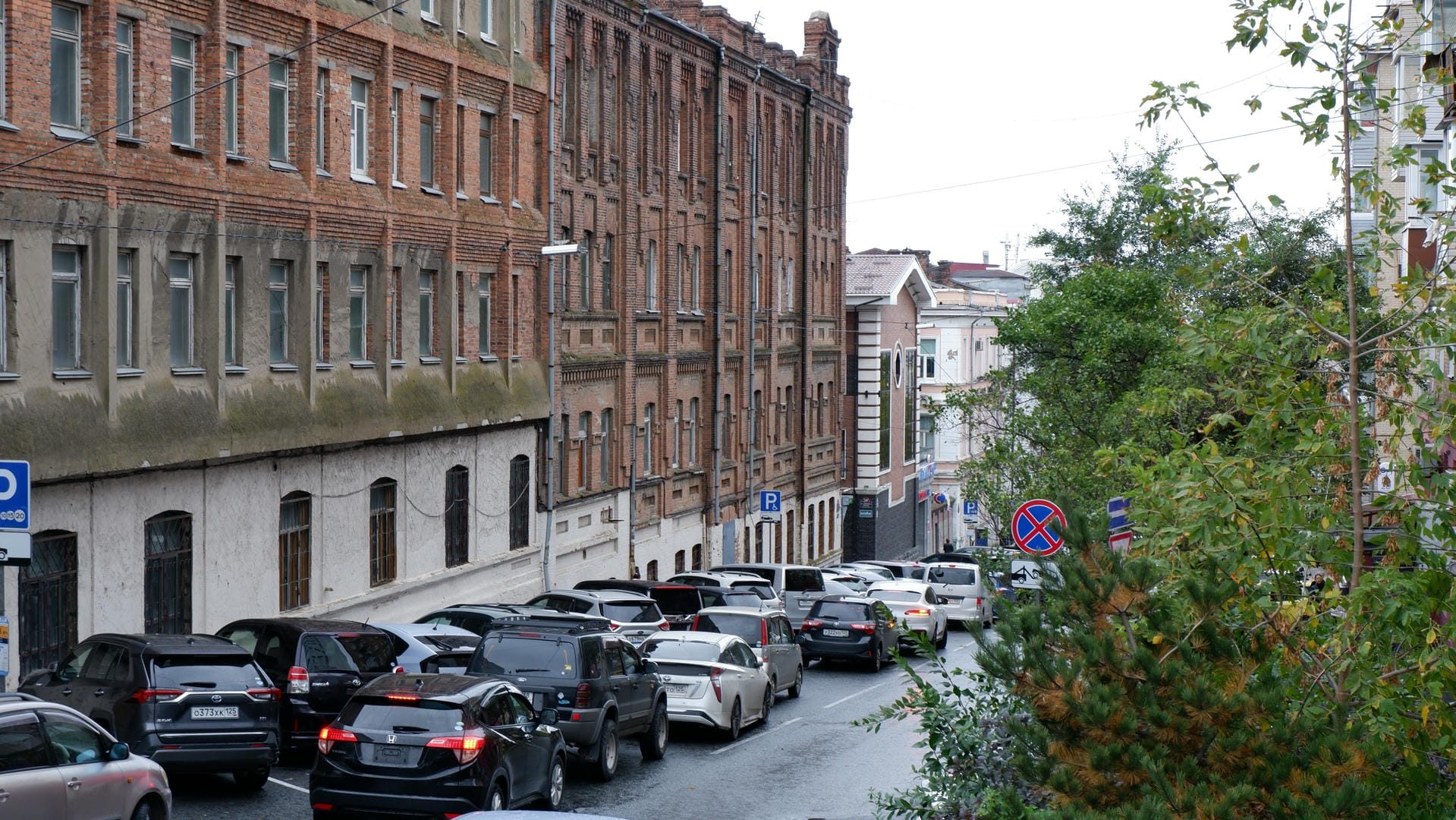 People moving in front of a building, with a white van visible on the right side.
