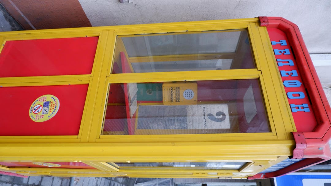 A red and yellow telephone booth labeled “TELEFON” on its door.