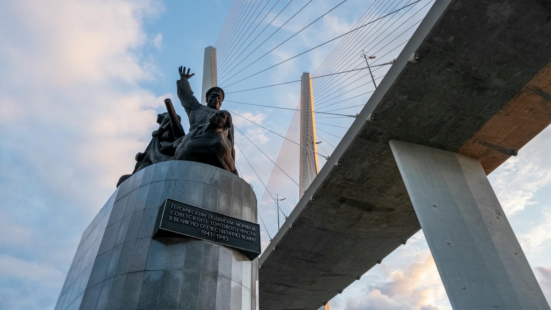 A modern sculpture under a bridge, with Russian inscription on its base.