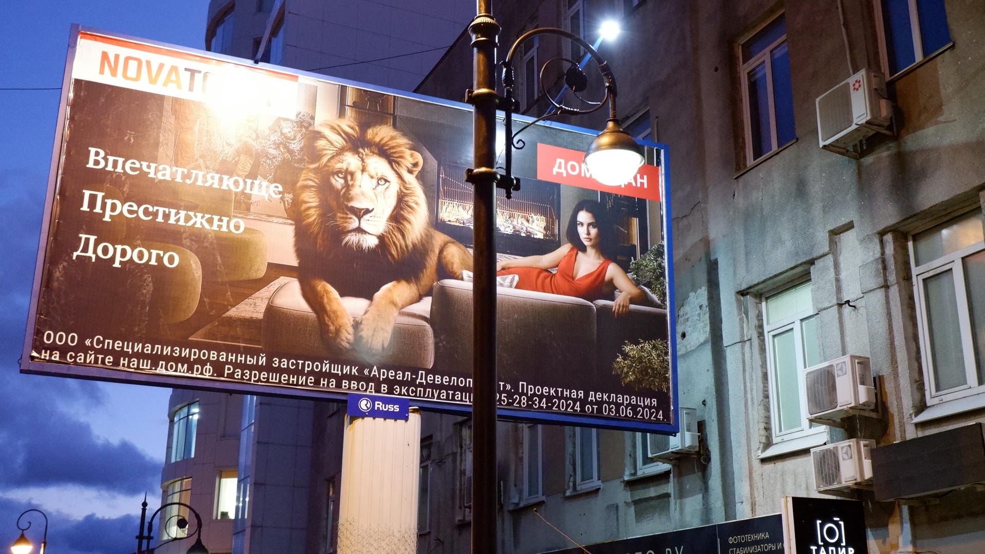 Billboard showing lion and female model imagery against building backdrop.