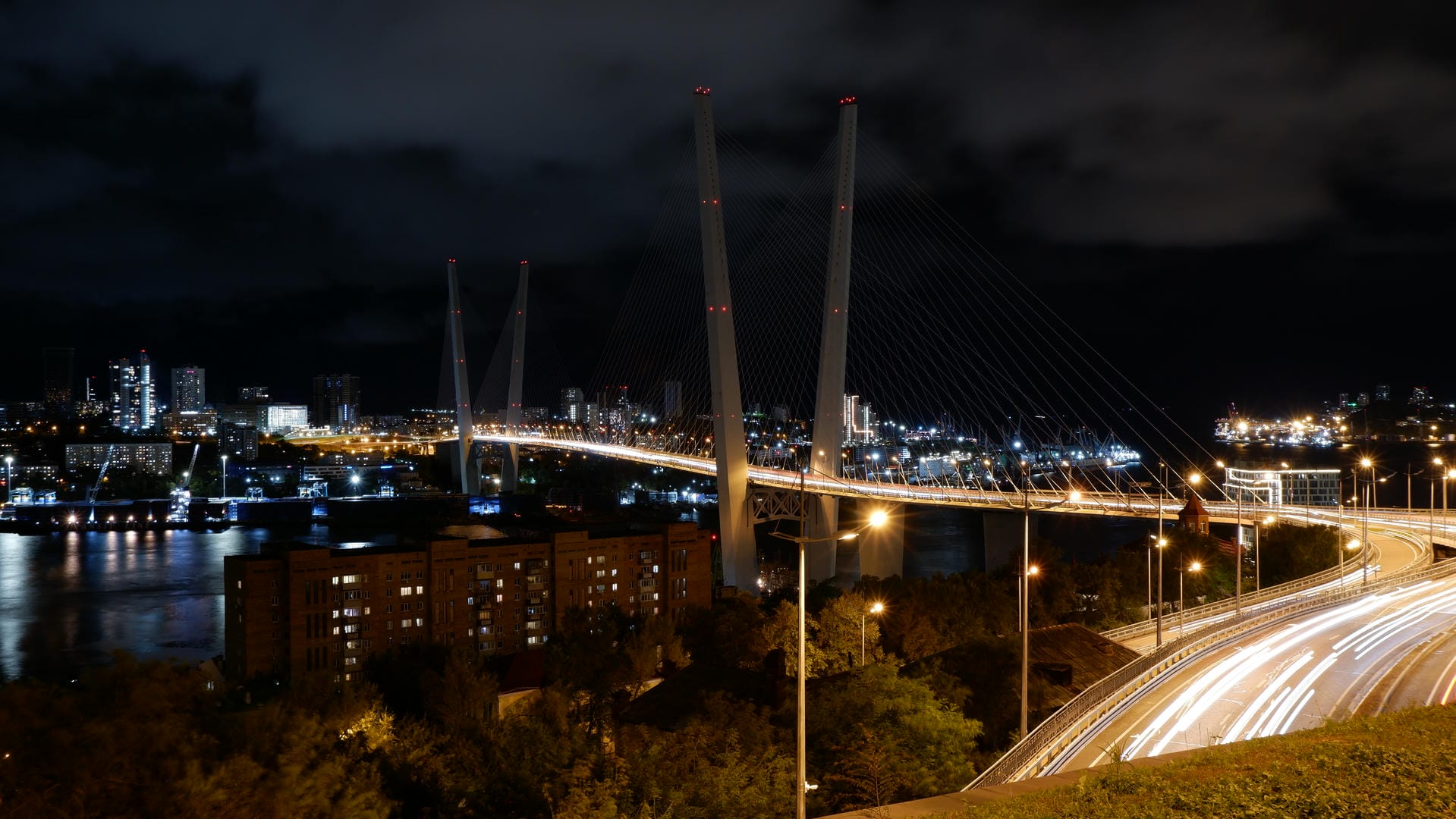 Night view of urban bridge with traffic flow and distant city lightscape.