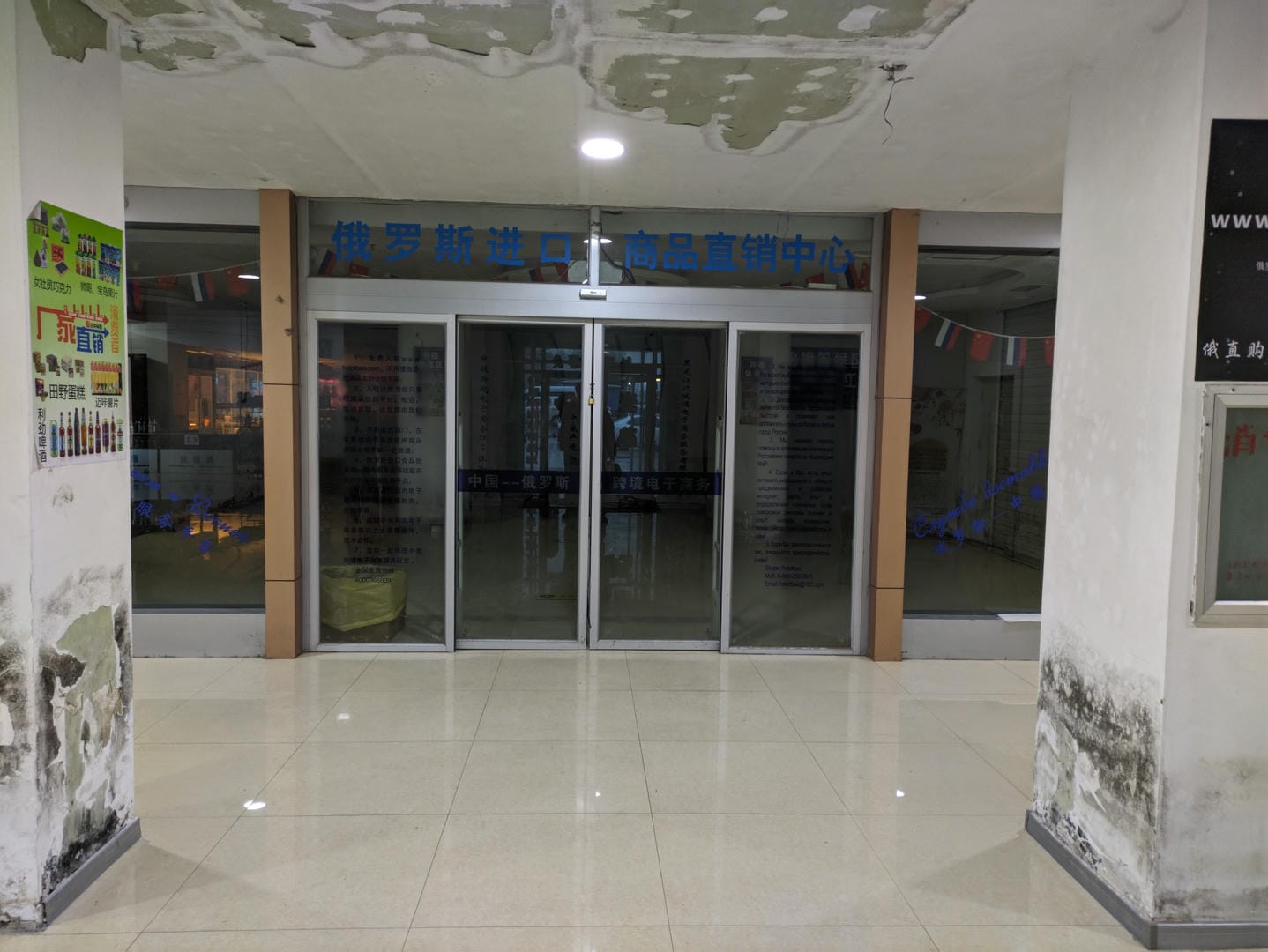 Interior scene with blue Chinese signage on glass door and peeling walls.