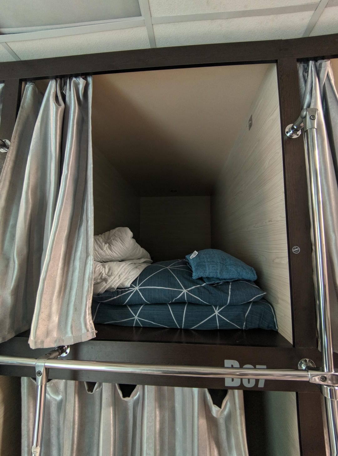 Capsule bed with blue-white bedding and curtain partitions.