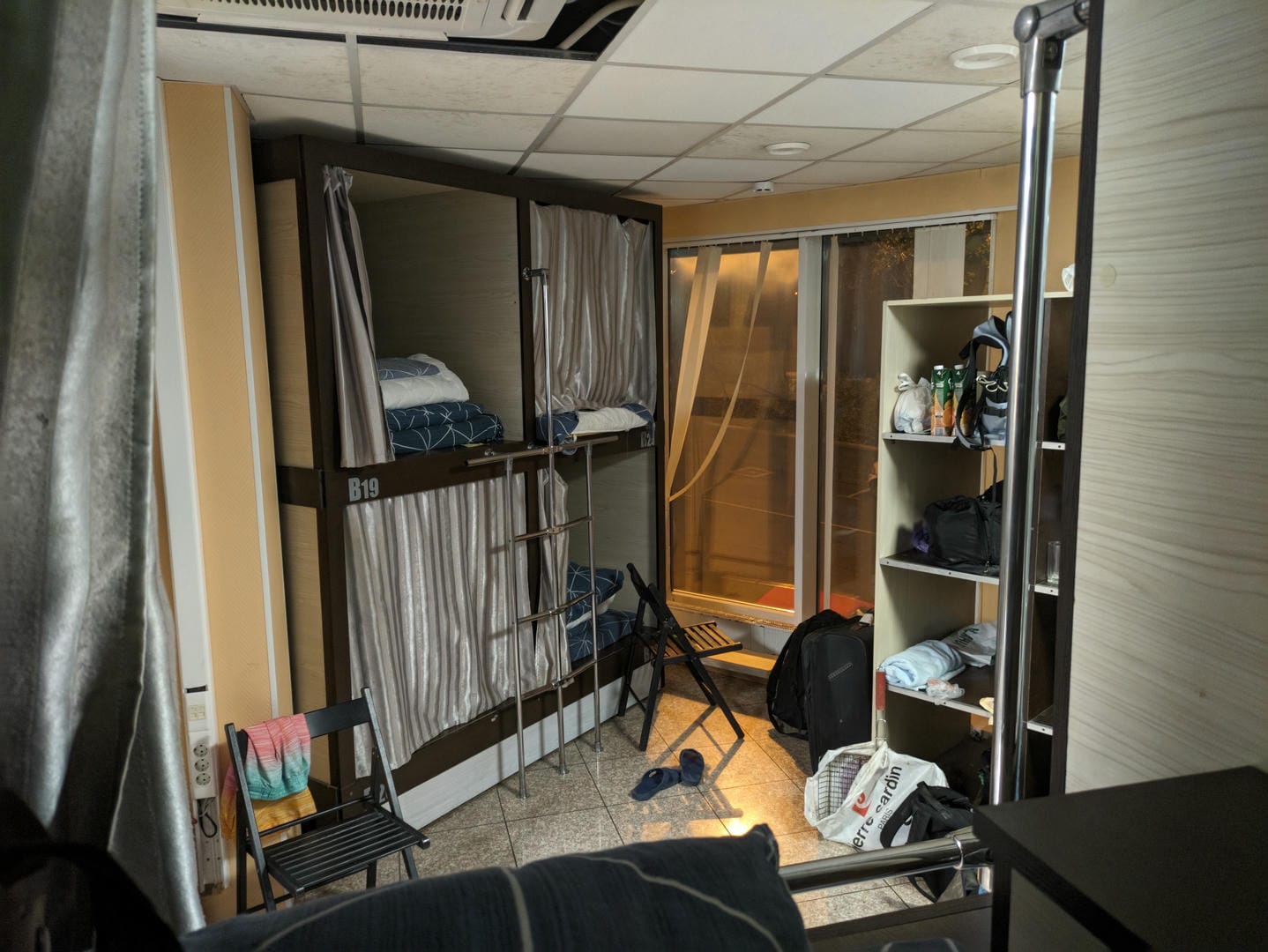 Dormitory room with curtained bunk beds and personal belongings.