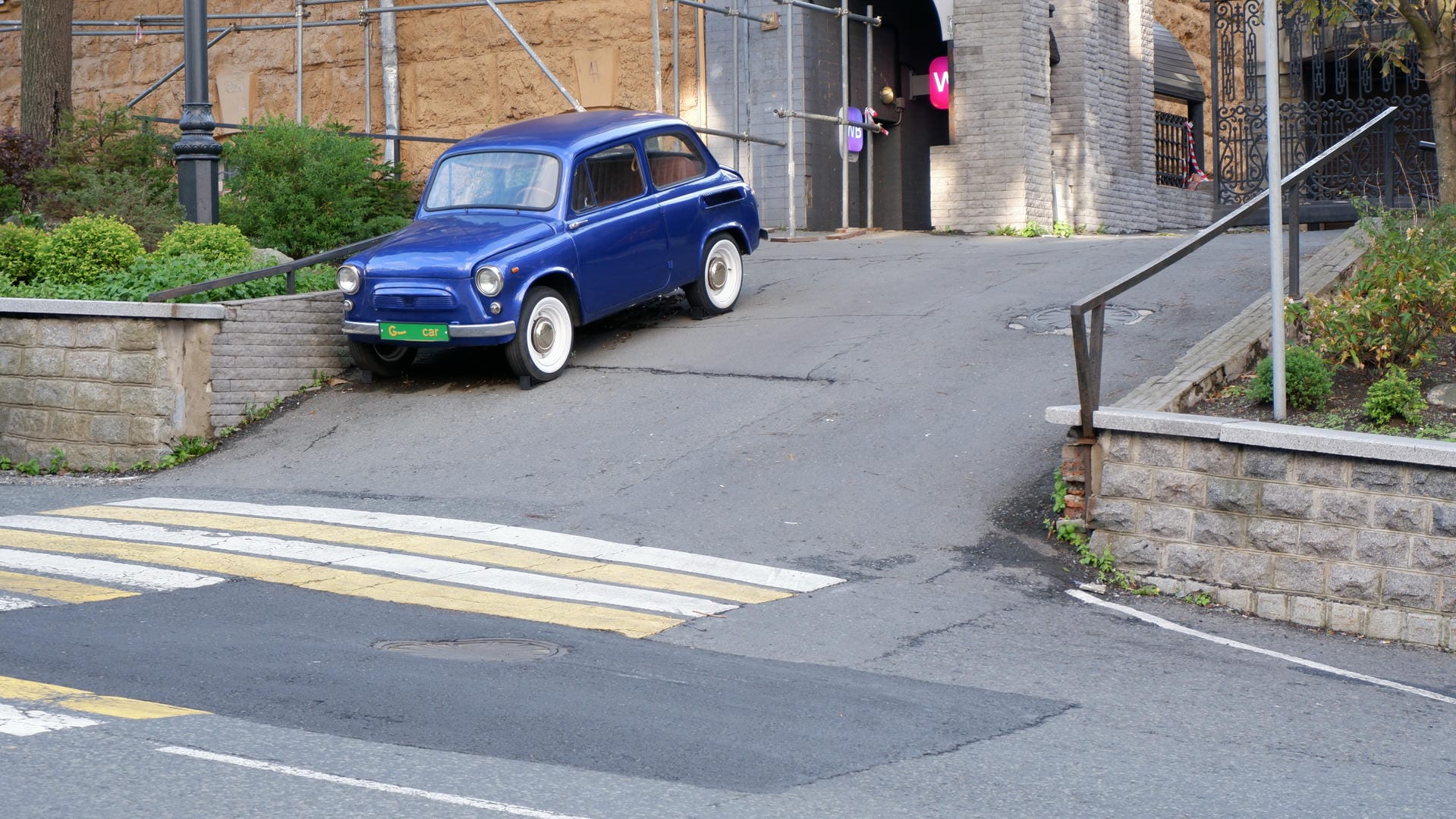 A blue car parked on a slope, facing left side of the frame.