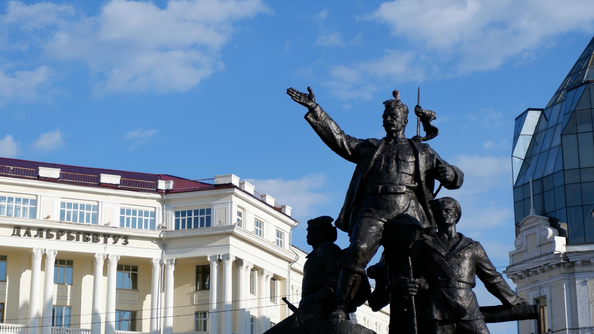Statue standing in square with multi-story buildings behind.