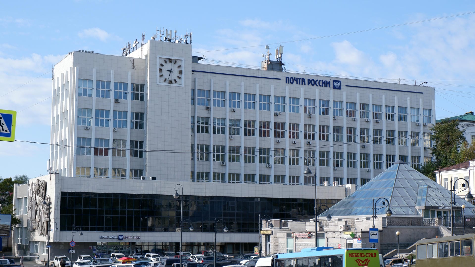 Large building marked “Почта России” with antennas and clock on roof.