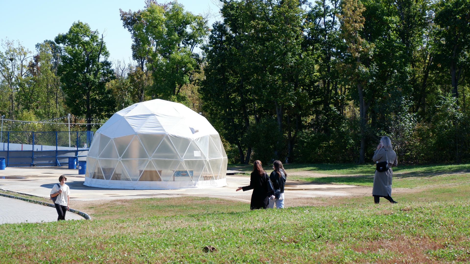 White domed structure on grassy area with people moving around.