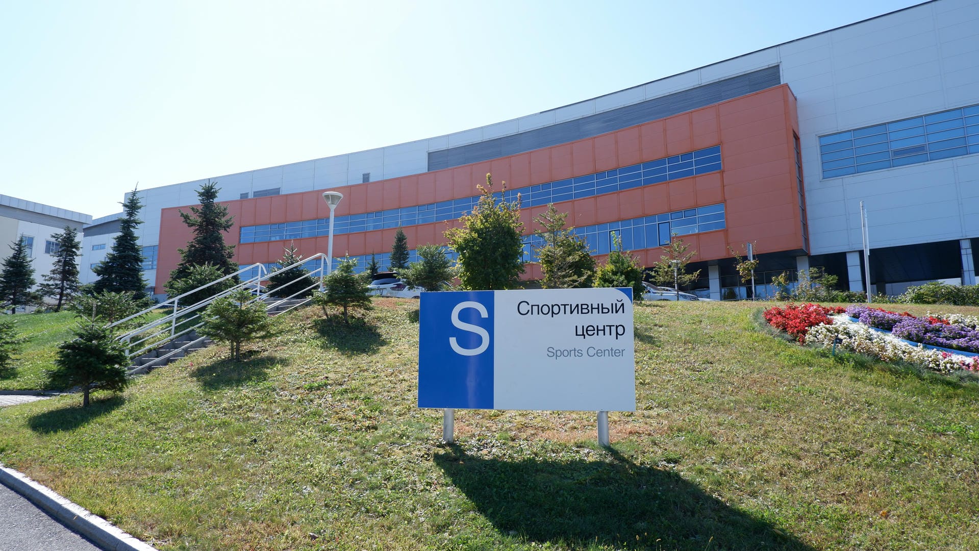 Sign reading “Sports Center” before orange-white building.