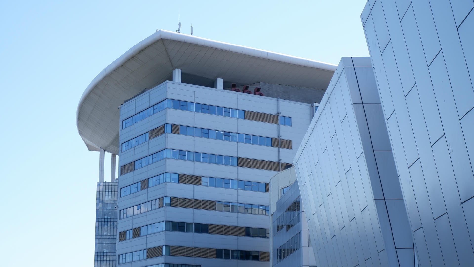 Modern building featuring circular platform structure on roof.