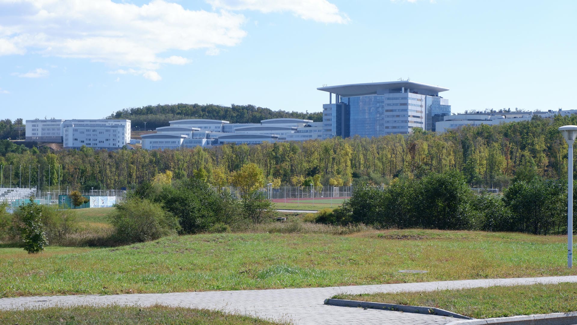 Distant buildings surrounded by green vegetation under clear sky.