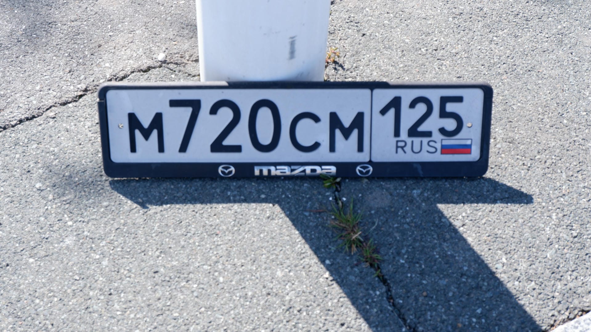 License plate M720CM 125 RUS lying on ground.