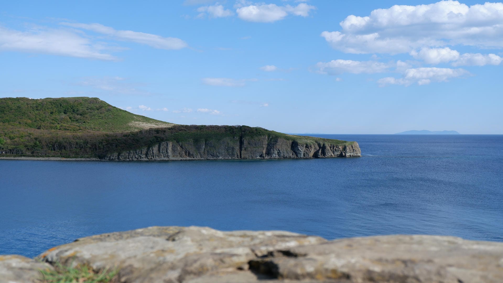 Blue sea and cliffs with rocky foreground.