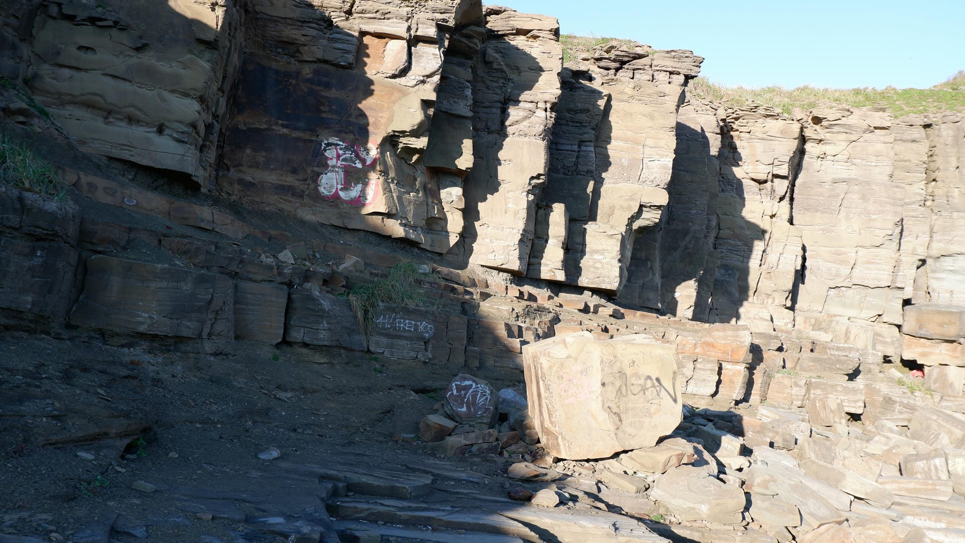 Graffiti-covered rock featuring red pattern and letters.