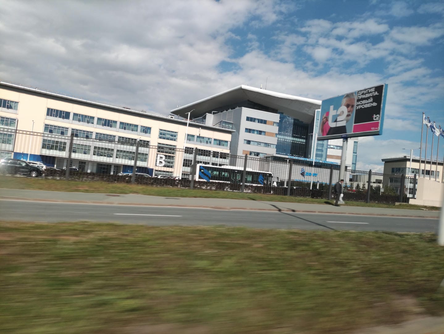 Modern roadside building with billboard and flags.