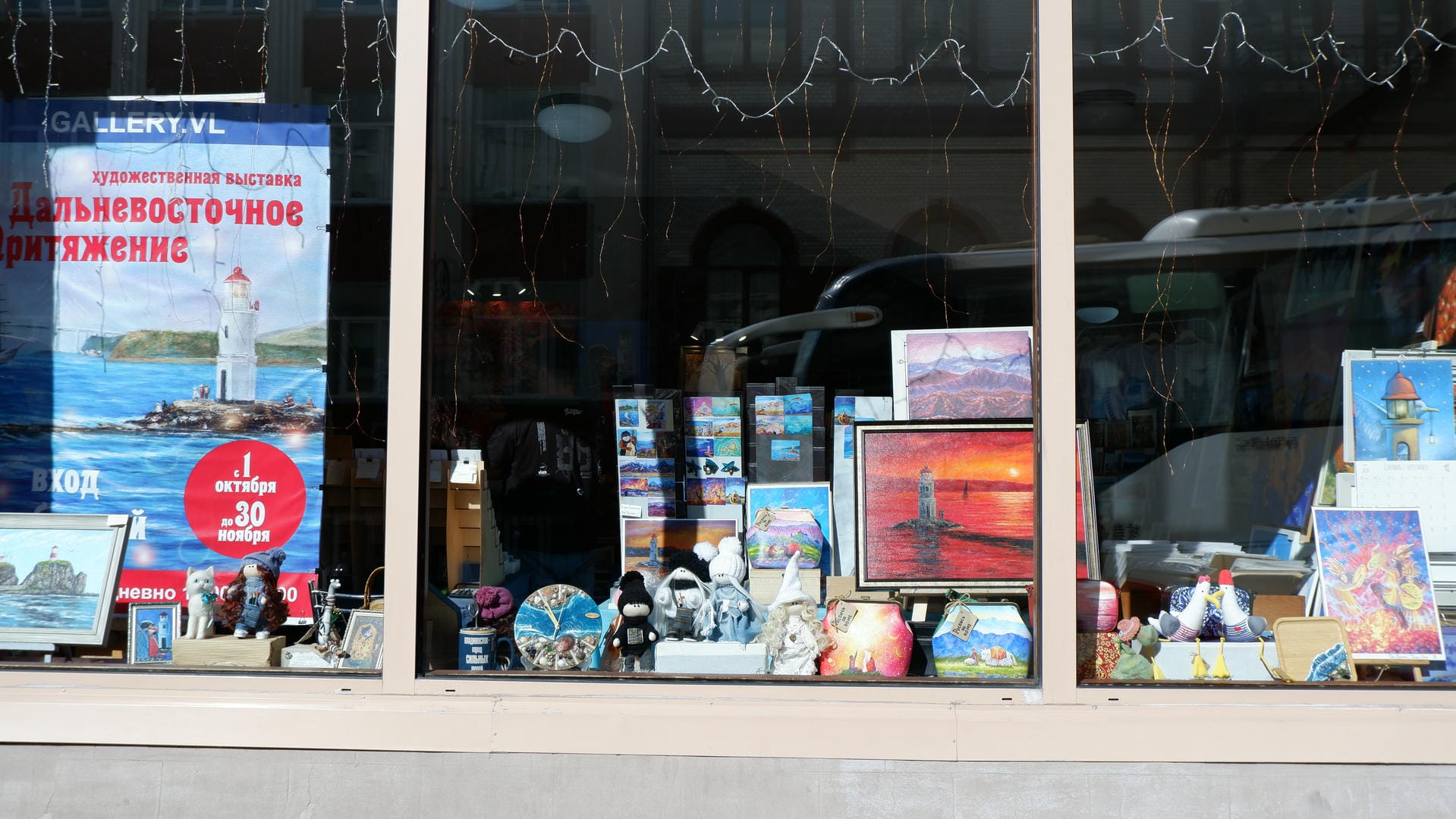 A shop window displaying various artworks and souvenirs, including paintings and sculptures.