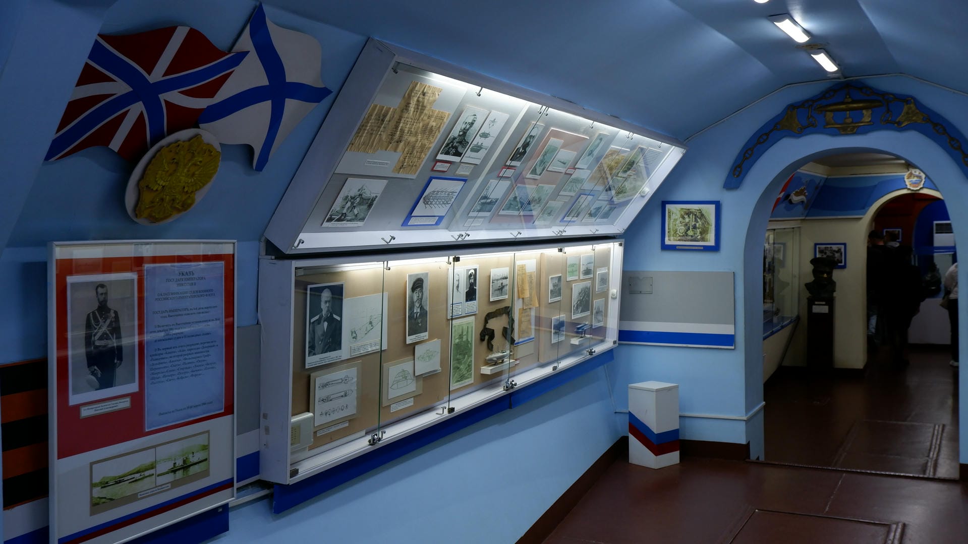 The interior of a museum displaying historical artifacts and photographs, with flags hanging on the walls.