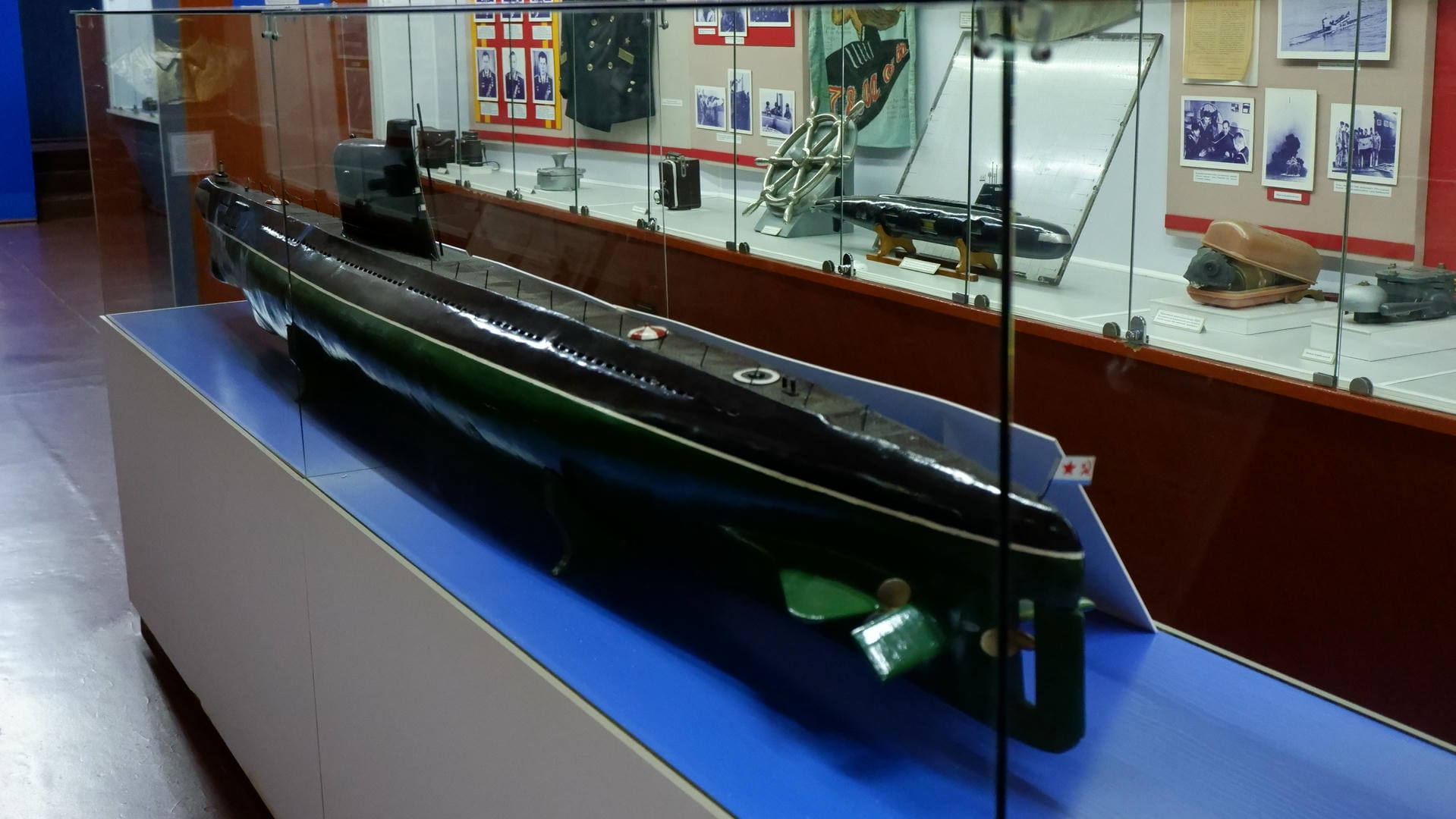 A model of a submarine placed inside a display case, surrounded by various exhibits.