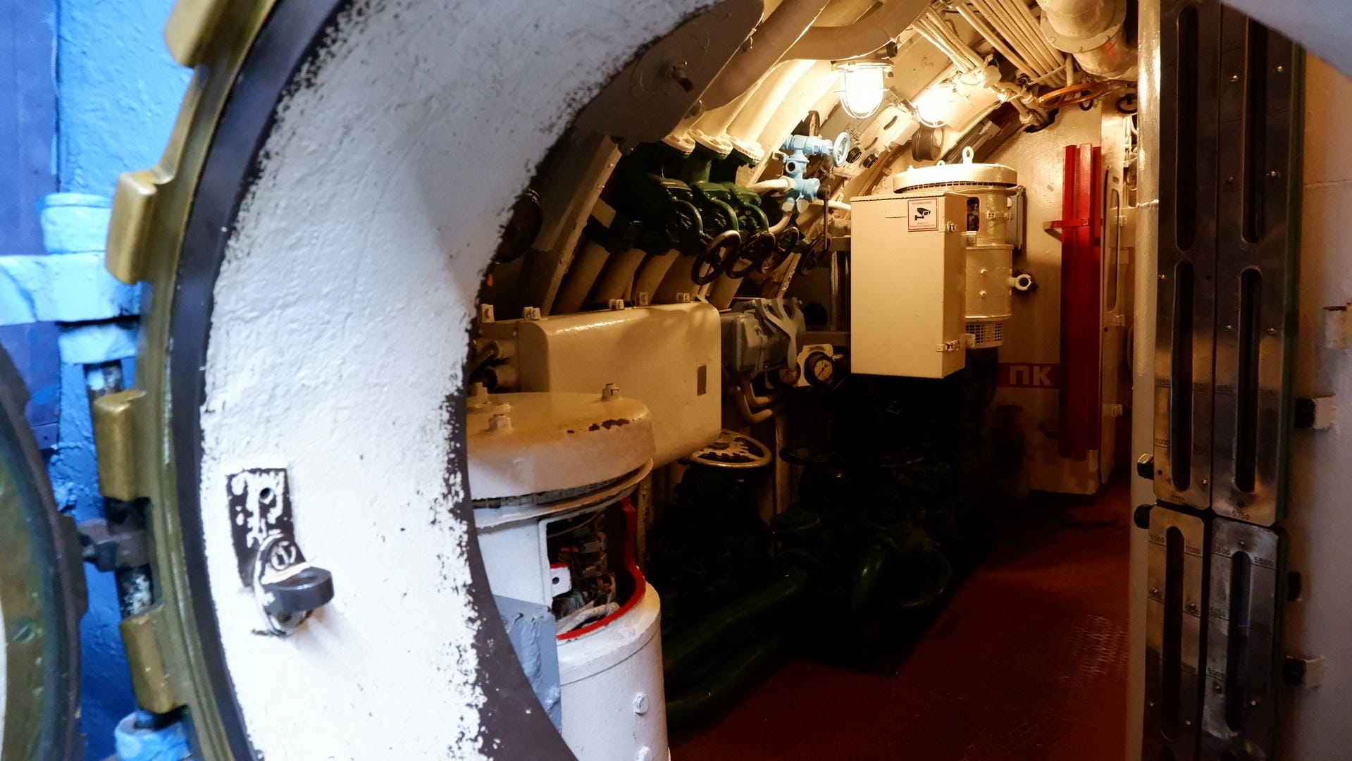 A narrow corridor with various pipes and equipment on both sides.
