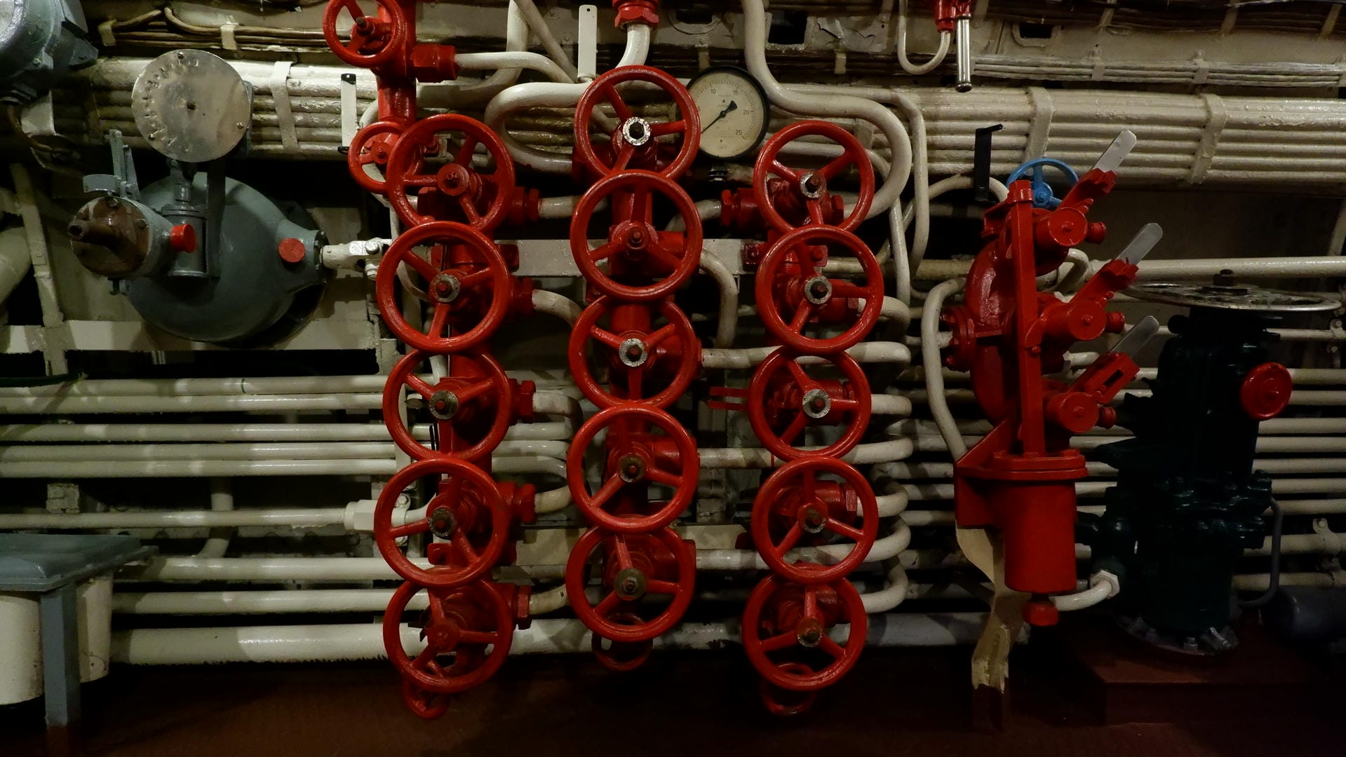 A mechanical device composed of red valves and pipes, with a dashboard in the background.