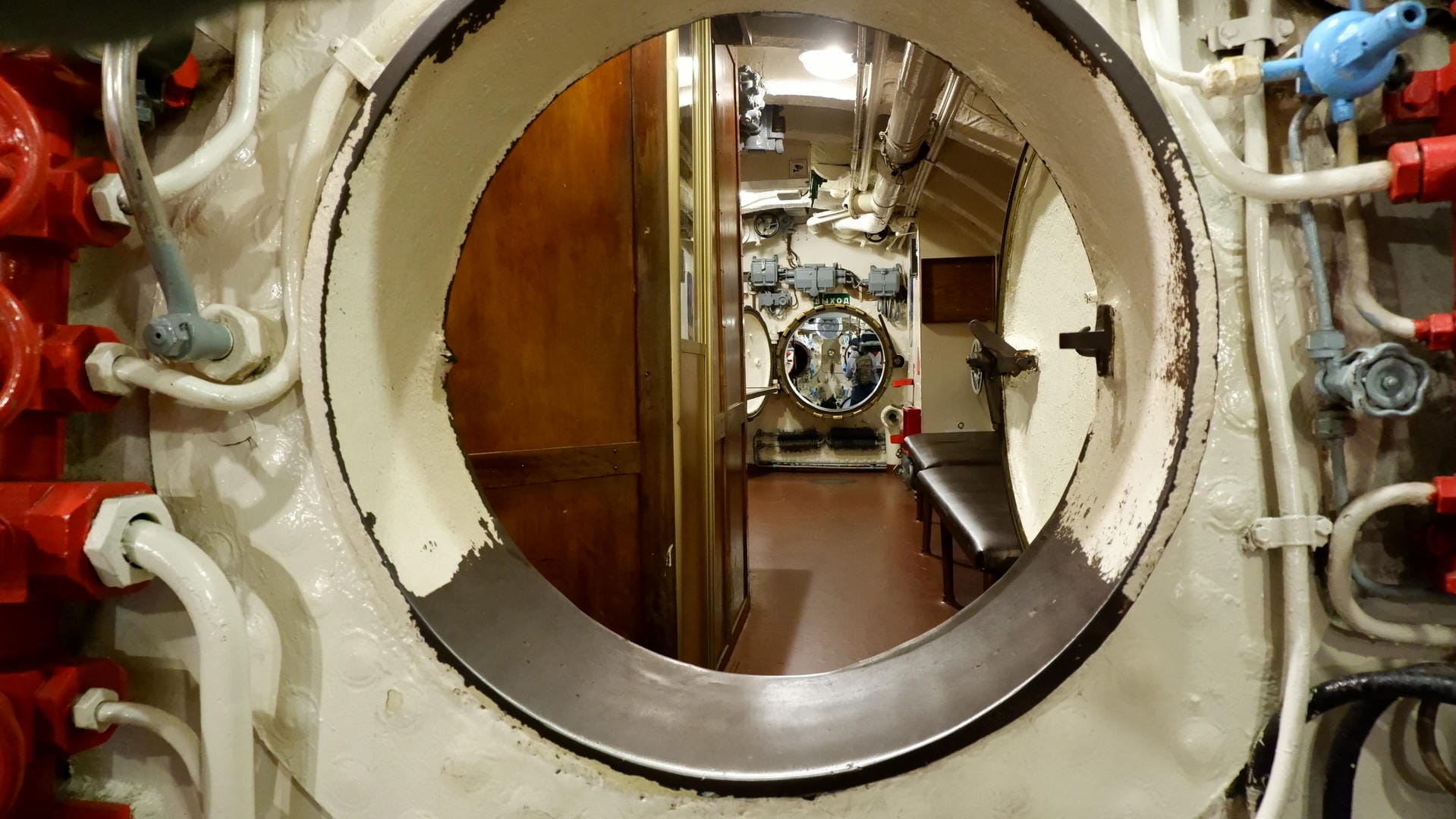 A circular hatch through which internal equipment and pipes are visible.