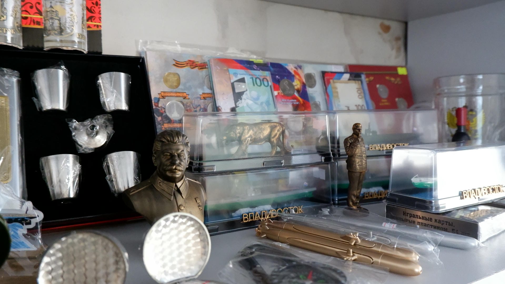 A table displays various souvenirs, including metal statues, coins, and books.