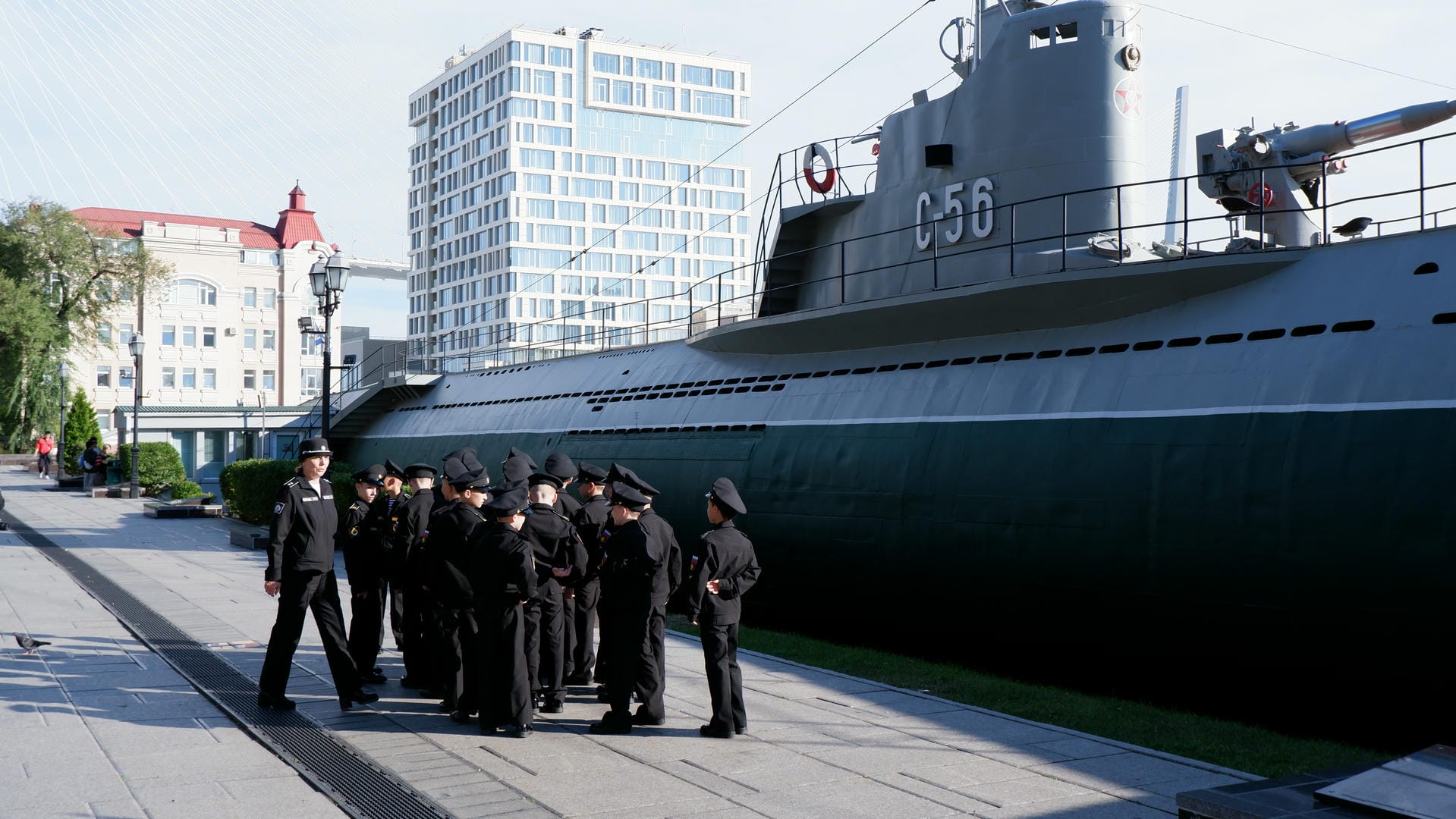 Children line up in two rows, the front row squatting and the back row standing, with an adult nearby.