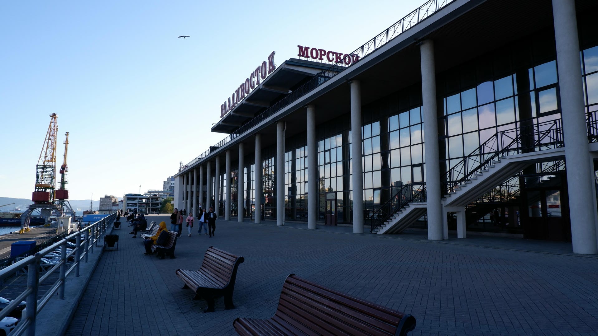 The street is filled with many vehicles, with a church with a golden dome ahead, and a suspension bridge in the distance.