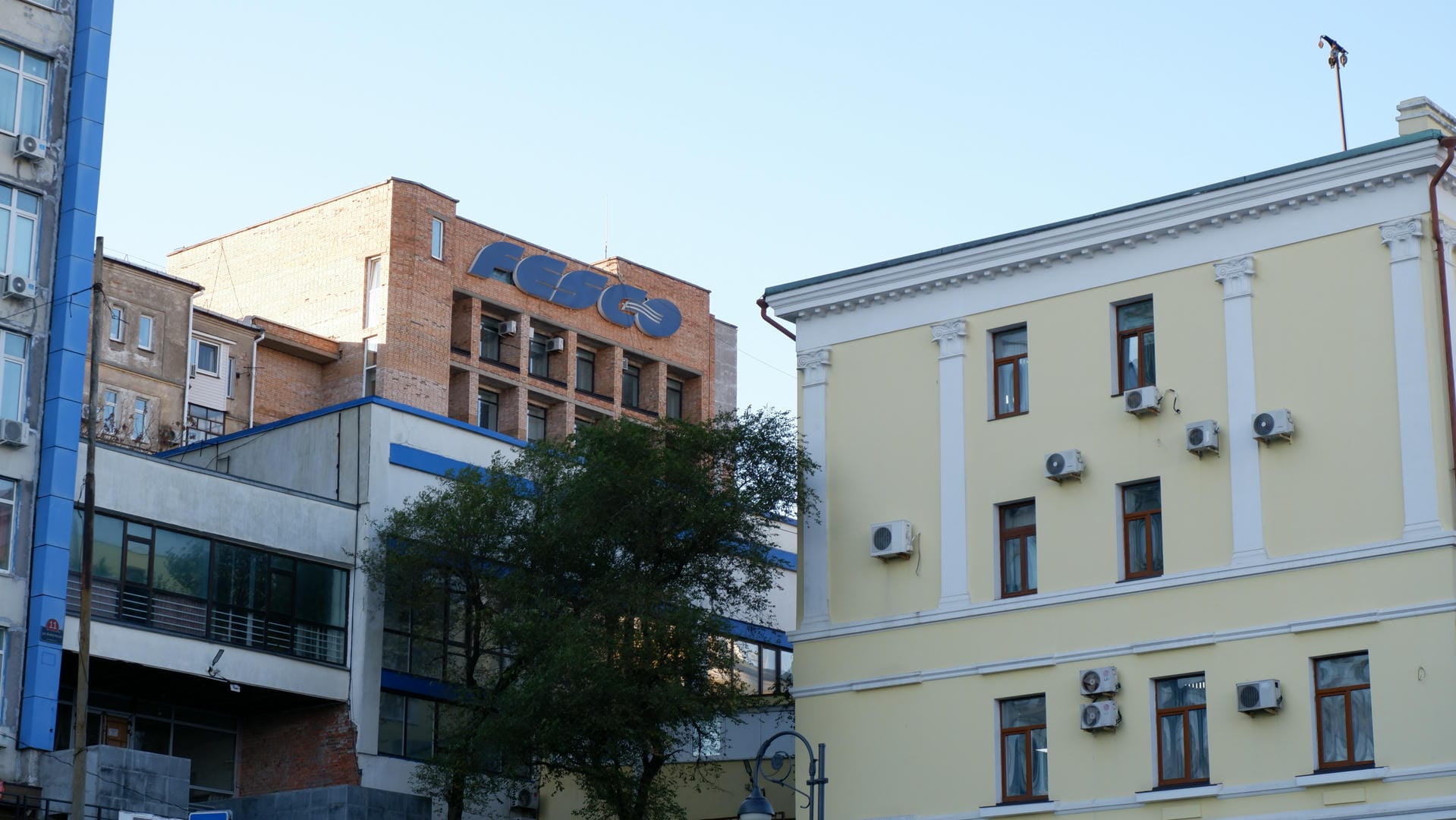 The exterior wall of a building bears the “FESCO” logo, next to a yellow building.
