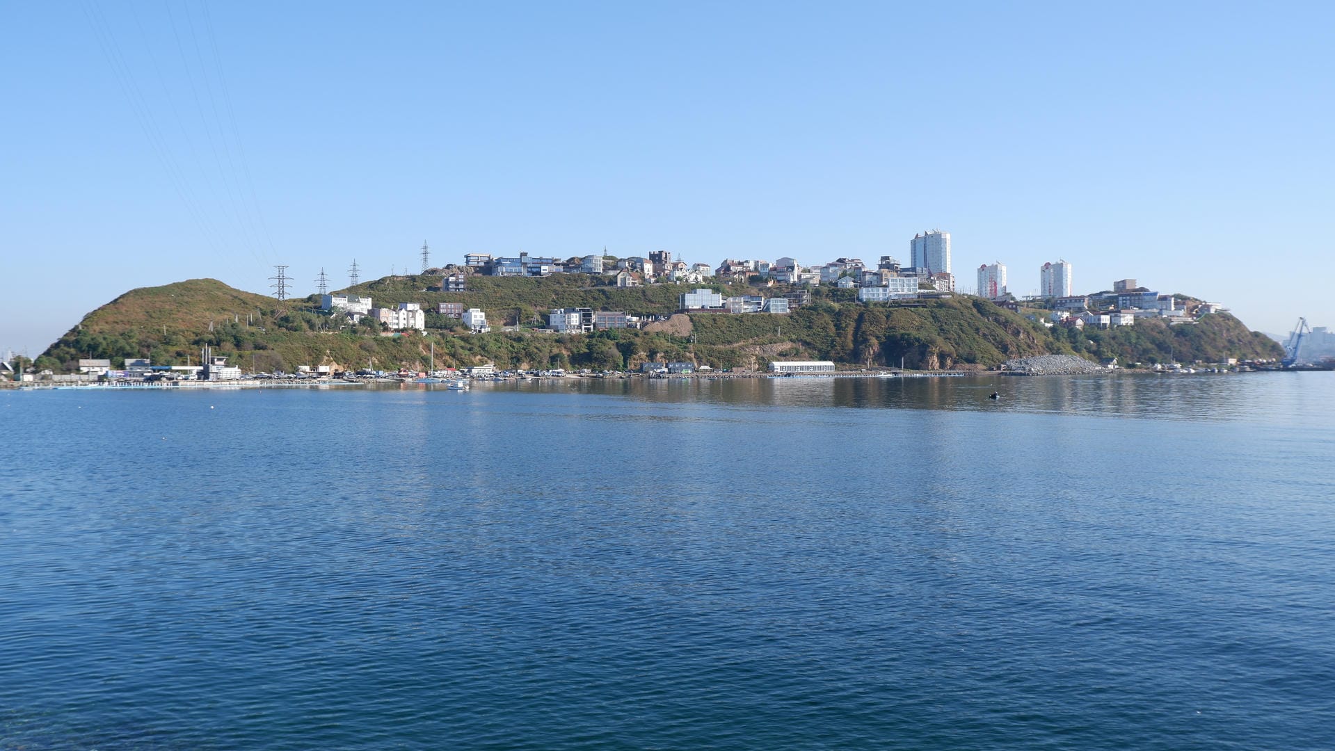 Many houses are built on a small hill, with a tranquil body of water at the foot of the hill.