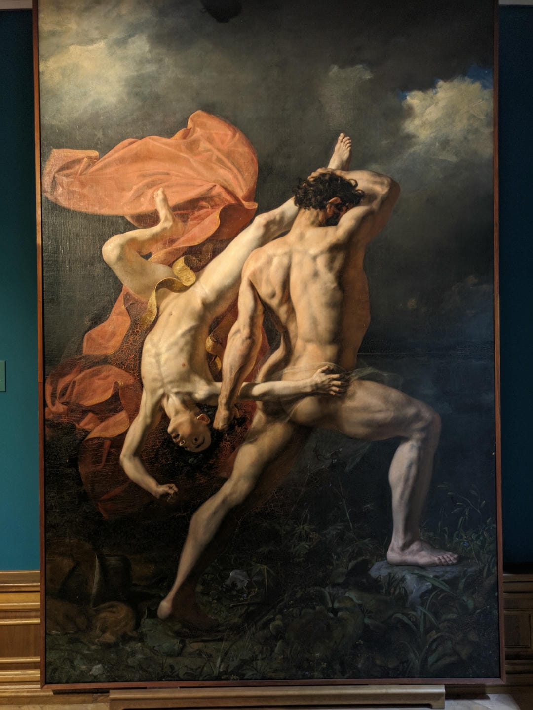 A painting depicts a muscular man fighting another fallen man, with red fabric fluttering in the background.