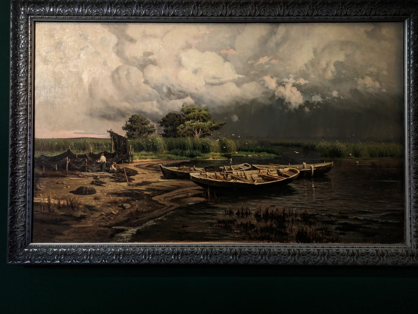 A painting depicts a riverside scene, with small boats docked along the shore, distant trees, and clouds in the sky.