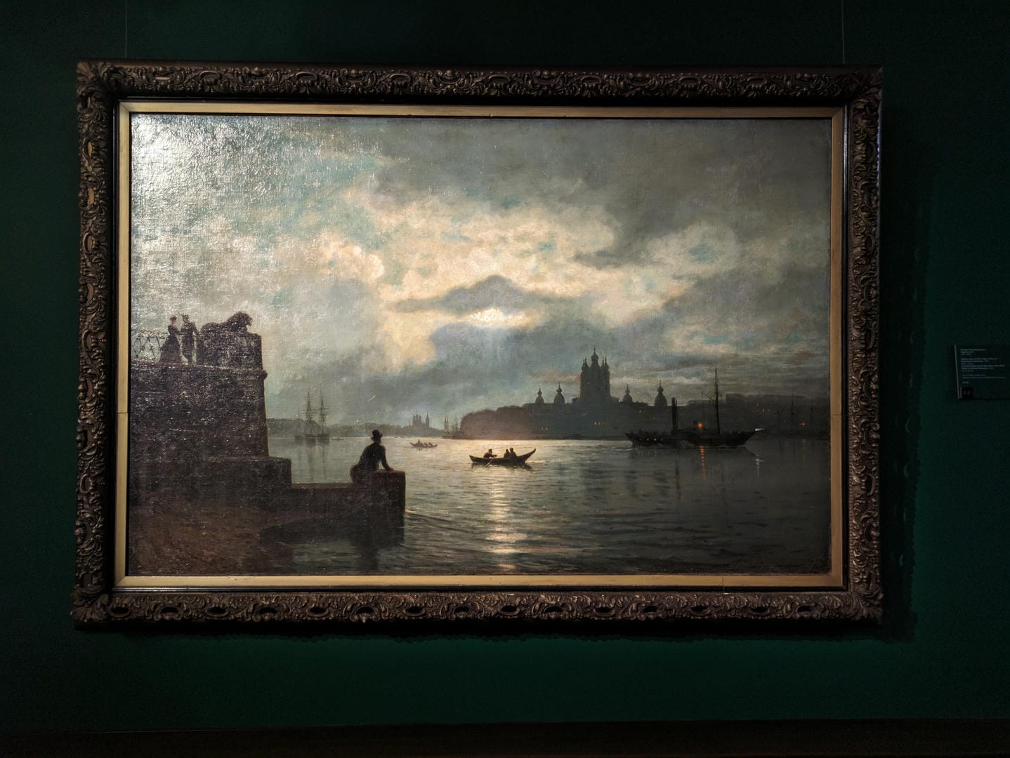 A painting depicts a city nightscape, with a river, boats, and distant urban architecture.