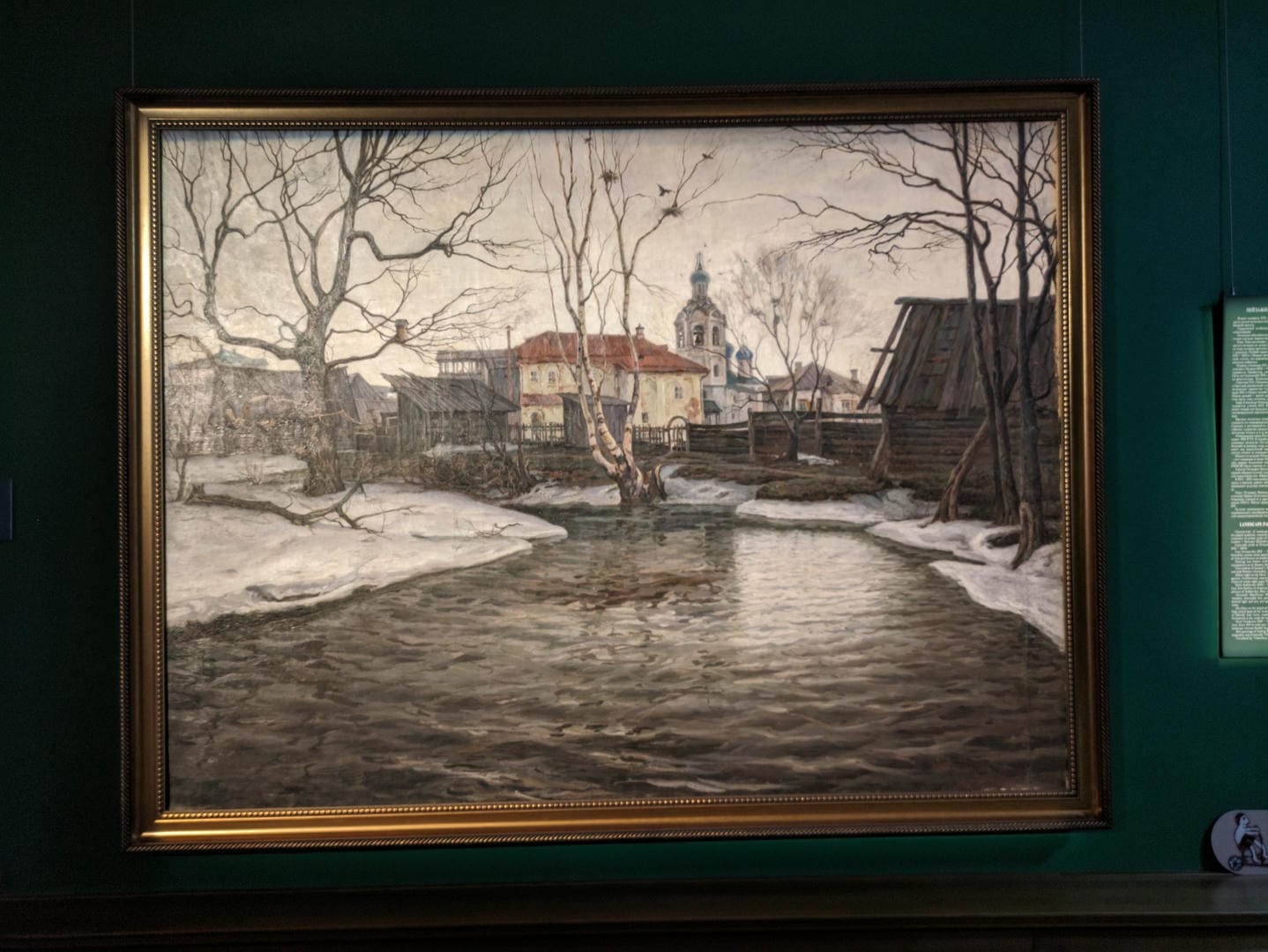 A painting depicts a winter countryside scene, with a stream, bare trees, and snow-covered ground.