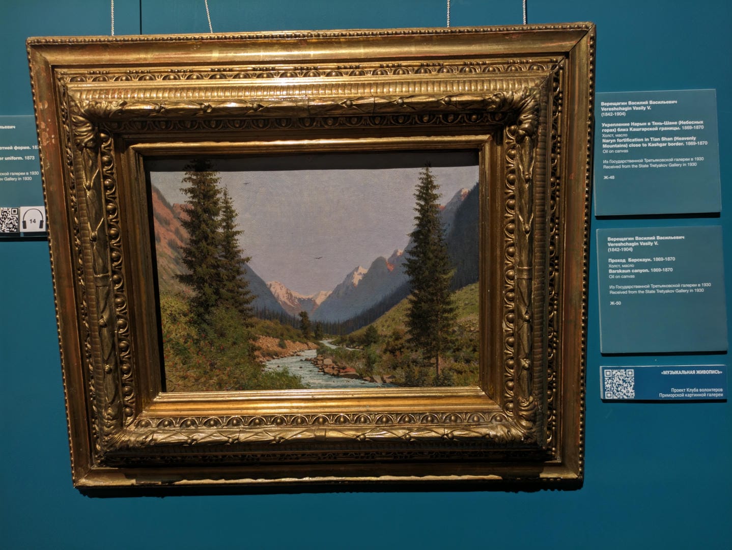 A painting depicts a river in a valley, with tall pine trees and distant mountains.