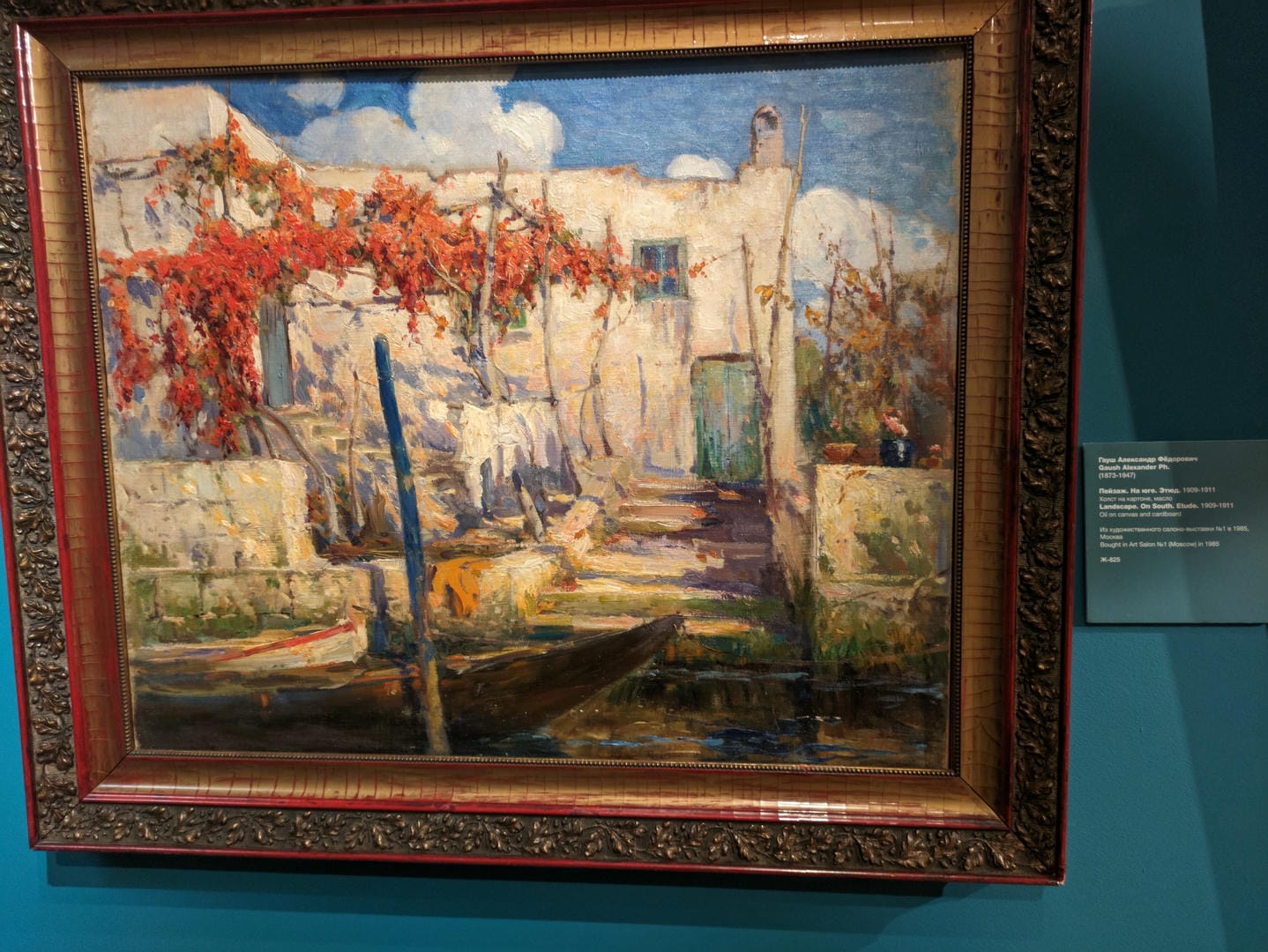 A framed oil painting depicts houses by the water, with red trees and docked boats.