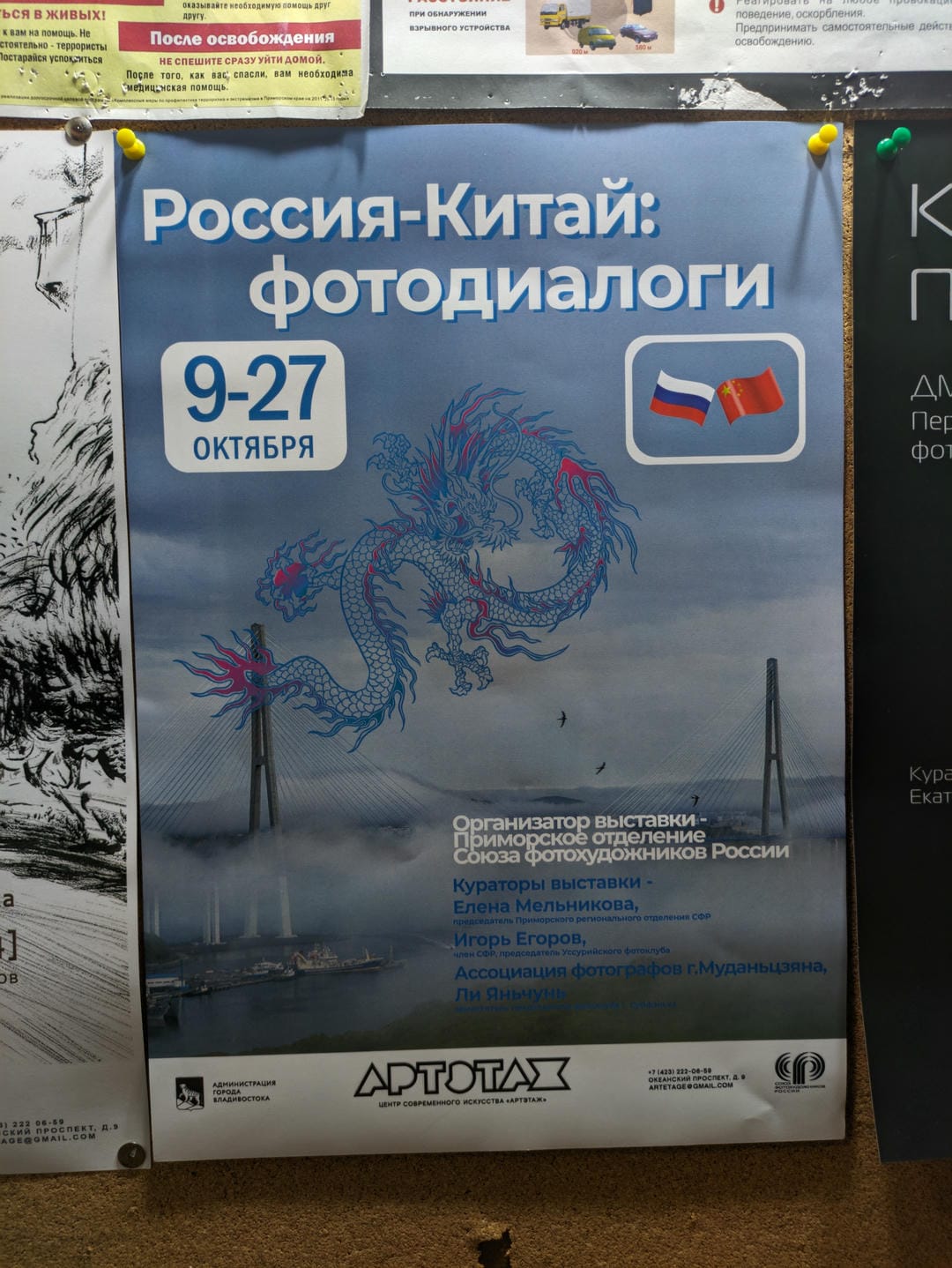 A poster reads “Russia-China: Photographic Dialogue,” dated October 9-27, with dragon motifs and bridges in the background.