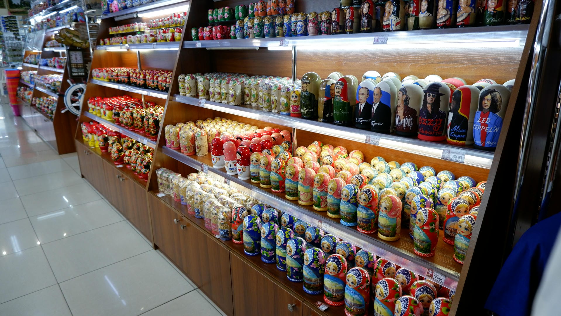 A store shelf displays many colorful Russian nesting dolls of varying sizes, neatly arranged.