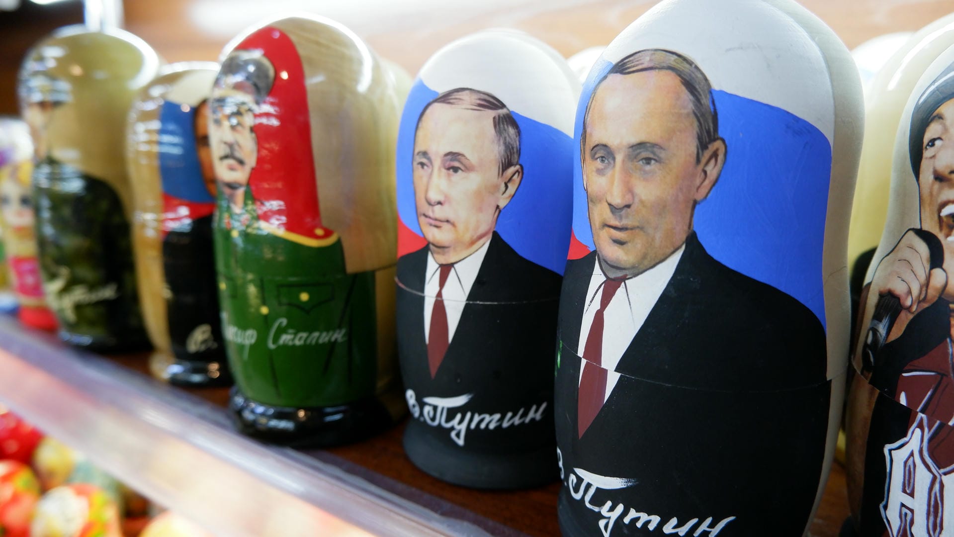 Russian nesting dolls featuring portraits of famous people, including military uniforms and suits with ties.
