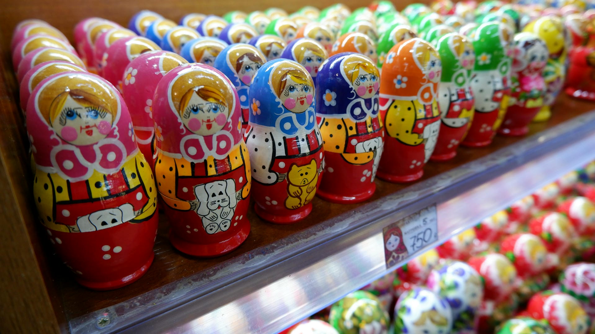 Multiple vibrant Russian nesting dolls are neatly arranged on the shelf, each with unique colors and patterns.