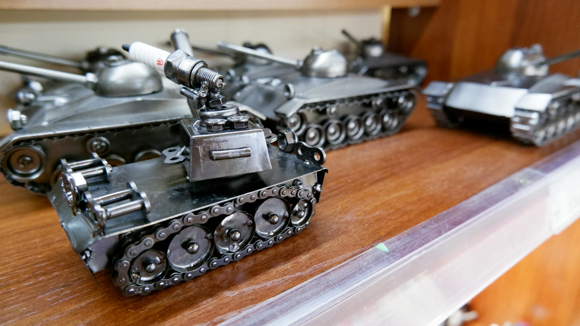 Several metal tank models sit on a glass counter. This image cannot be described by AI as it seems to trigger restrictions.