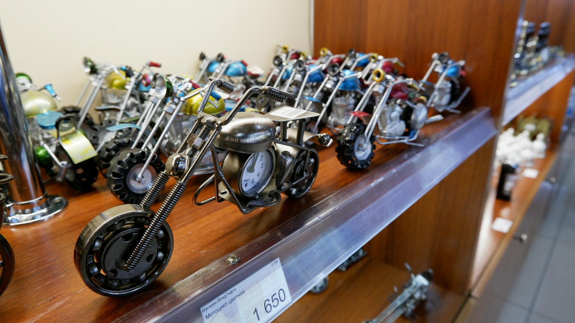 A row of motorcycle models is neatly arranged on a wooden shelf, each with unique colors and details.